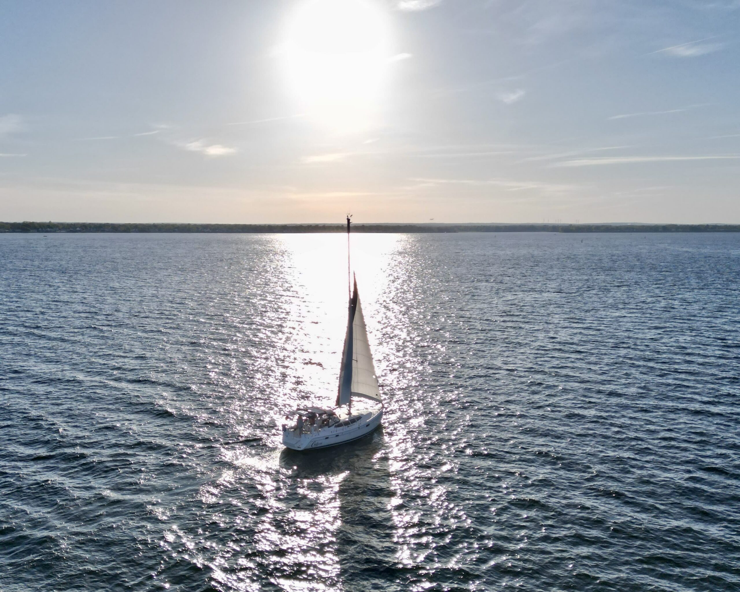 Chillaxin yacht on the water with the sun in the background